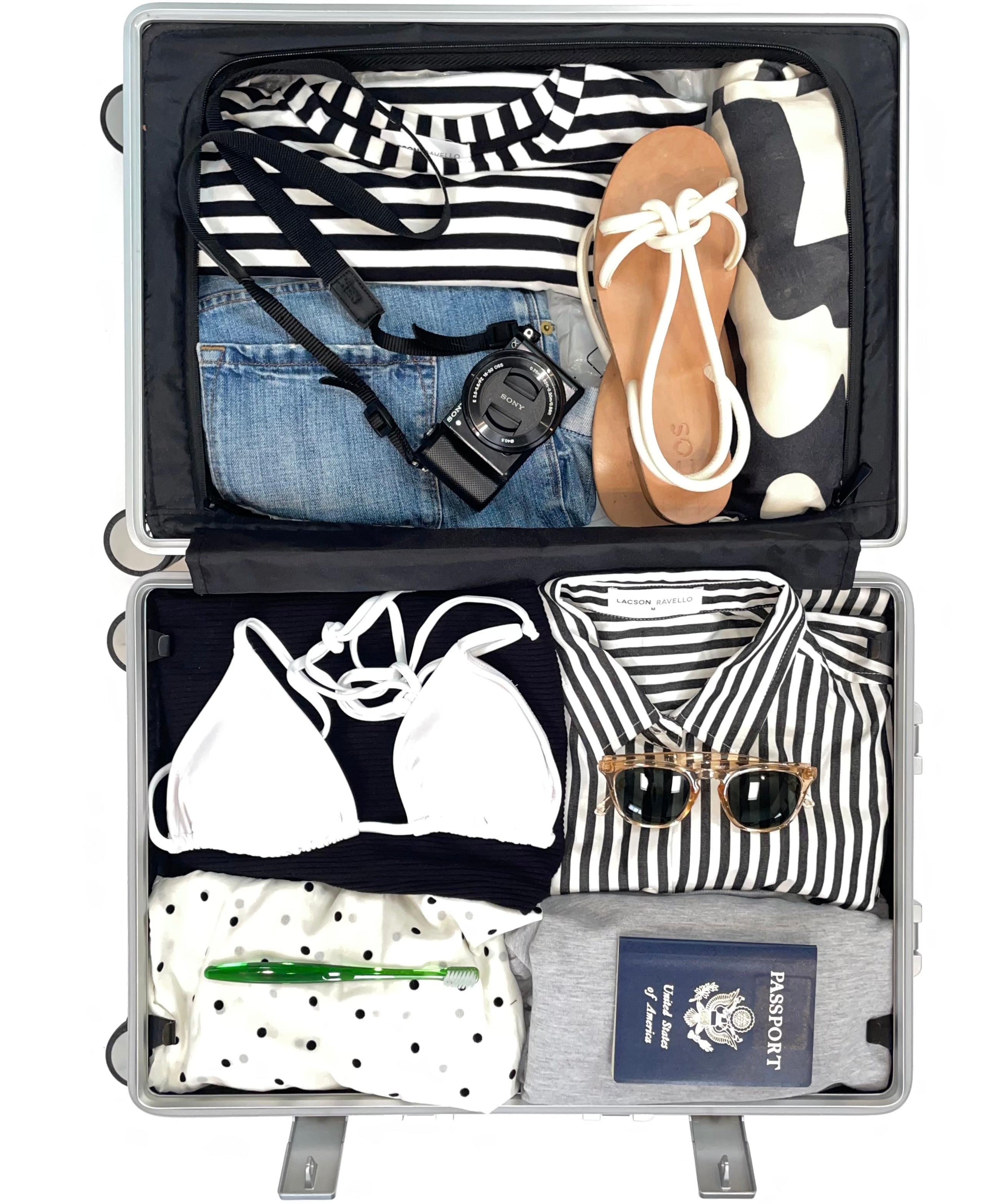 Open suitcase packed with black, white, and striped travel clothing