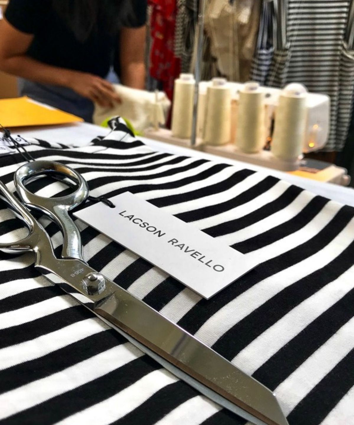 Black-and-white striped fabric being cut with shears for a Lacson Ravello production run